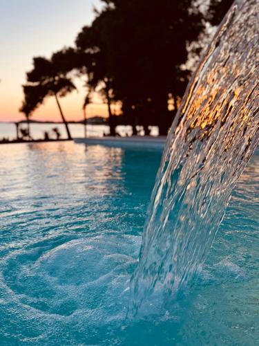 a water fountain in a pool with a beach in the background at SeeSea Hotel in Vodice