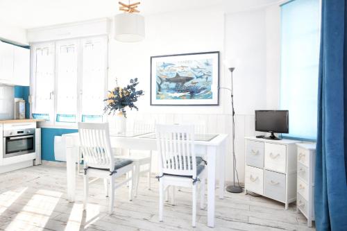 une salle à manger blanche avec une table et des chaises blanches dans l'établissement La Brise de Barneville - Appt proche plage, à Barneville-Carteret