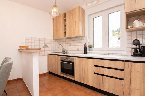 a kitchen with wooden cabinets and a sink and a window at Apartments Leonel by Locap Group in Piran