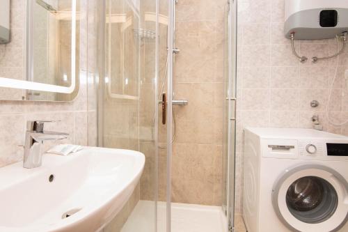 a bathroom with a shower and a sink and a washing machine at Apartments Leonel by Locap Group in Piran