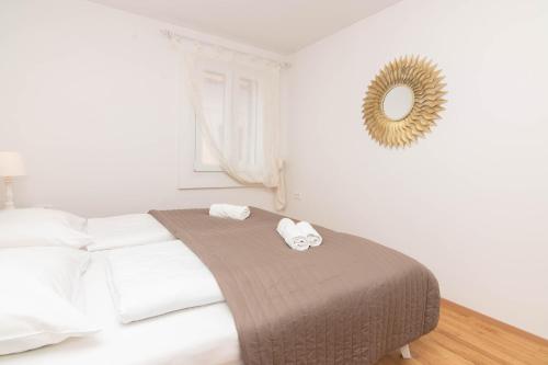a white bedroom with a bed with two towels at Apartments Leonel by Locap Group in Piran