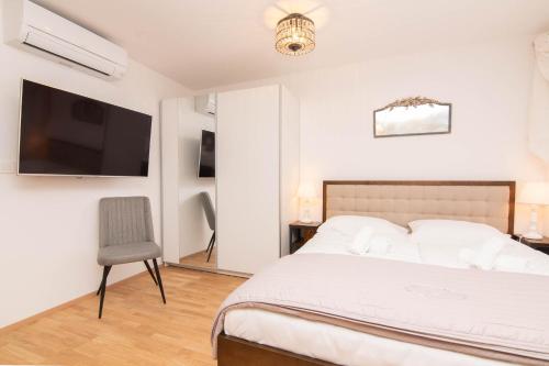a bedroom with a bed and a tv and a chair at Apartments Leonel by Locap Group in Piran