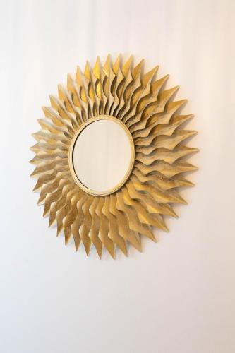 a mirror with a sunburst design on a wall at Apartments Leonel by Locap Group in Piran