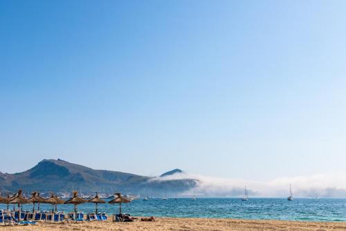 a beach with a group of umbrellas and the ocean at Cabot Romantic- Adults Only in Port de Pollensa