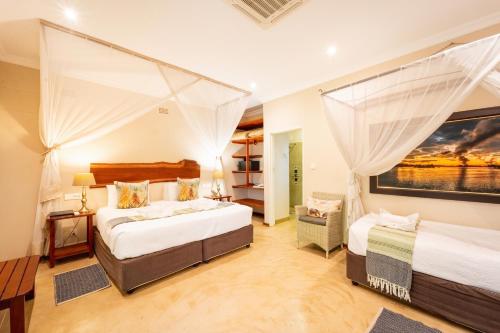a bedroom with two beds and a large painting on the wall at Bayete Guest Lodge in Victoria Falls