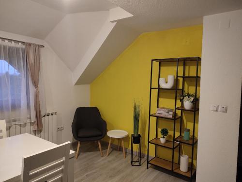 a room with a chair and a yellow wall at Apartment Lana in Rakovica