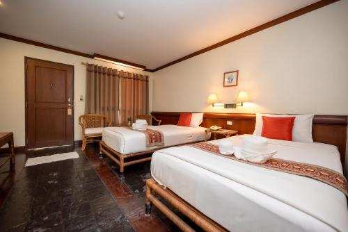 a hotel room with two beds and a table at Comsaed River Kwai Resort in Kanchanaburi