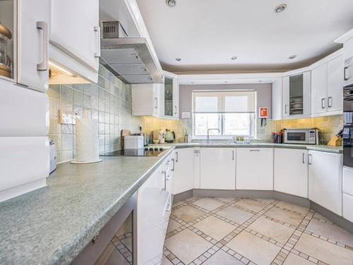 a large white kitchen with white cabinets and appliances at City Centre Town House w Parking - Pass the Keys in Chichester
