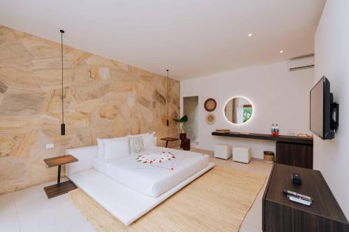 a bedroom with a white bed and a stone wall at Ycona Eco-Luxury Resort, Zanzibar in Dikoni