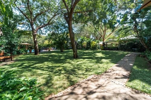 a park with trees and a sidewalk at Bayete Guest Lodge in Victoria Falls