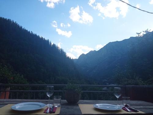 a table with two glasses and a view of mountains at Albergo diffuso La Marmu Osteria della Croce Bianca in Marmora