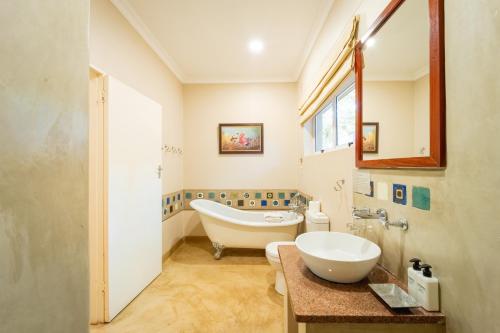 a bathroom with a tub and a sink at Bayete Guest Lodge in Victoria Falls