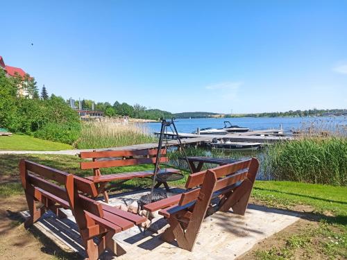 a group of benches sitting next to a lake at P R A T U M 17 Apartament z widokiem na jezioro in Mikołajki