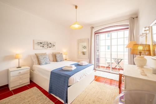 a white bedroom with a bed and a window at GuestReady - Coastal Bliss in Praia de Troia in Troia
