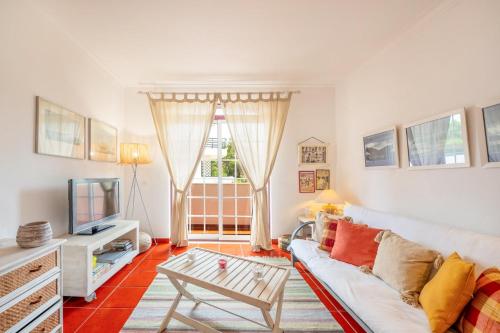a living room with a white couch and a tv at GuestReady - Coastal Bliss in Praia de Troia in Troia