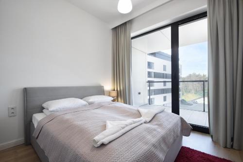 - une chambre blanche avec un lit et une grande fenêtre dans l'établissement RentPlanet - Apartamenty Shellter, à Rogowo