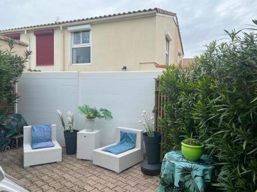 eine Terrasse mit zwei Stühlen und Pflanzen vor einem Haus in der Unterkunft Location d'un pavillon de vacances in Marseillan