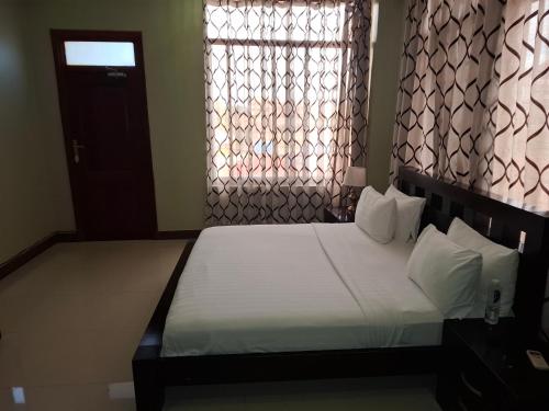 a bedroom with a bed and a window and a door at Flomi Hotel in Morogoro