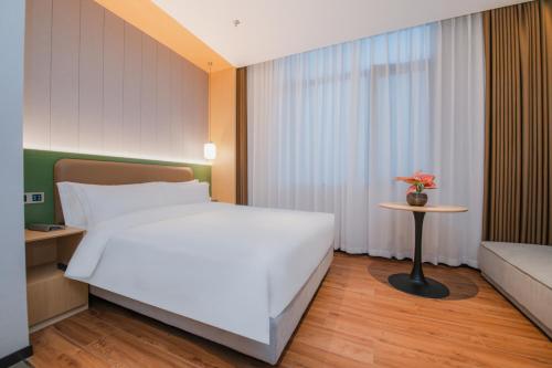 a bedroom with a large white bed and a table at Mehood Hotel Jining Zoucheng in Zoucheng