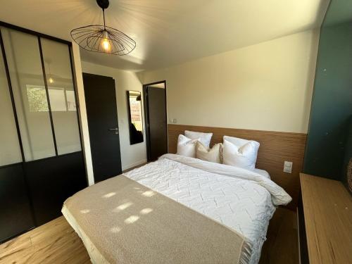 une chambre avec un lit avec des draps blancs et des oreillers dans l'établissement Appartement Proche Hôpital, Jardin privatif, à La Tronche
