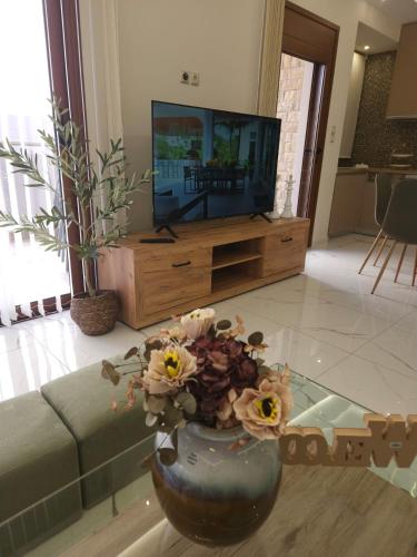 a living room with a vase with flowers in front of a tv at Agora Luxury Villa I in Loutraki