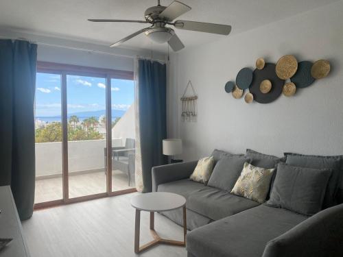 a living room with a couch and a ceiling fan at Garden City Seaview Las Americas in Playa Fañabe