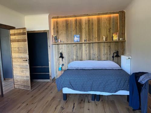 une chambre avec un lit et un mur en bois dans l'établissement Appartement de standing sur les hauteurs, à Briançon