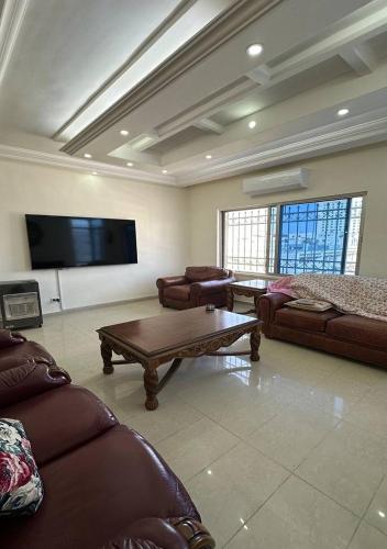 a living room with couches and a flat screen tv at Tlaa al ali amman 3 rooms furnished apartment المحكمة الدستورية in Umm Uthainah
