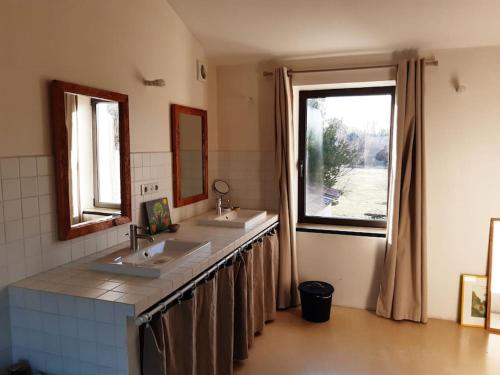 La salle de bains est pourvue de 2 lavabos et d'une grande fenêtre. dans l'établissement Grand mas provencal tout confort, à Carpentras