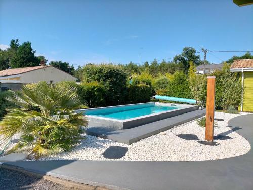a swimming pool in a yard with a palm tree at Gîte avec piscine jacuzzi espace bien-être partagés entre Bordeaux et Lacanau océan in Brach