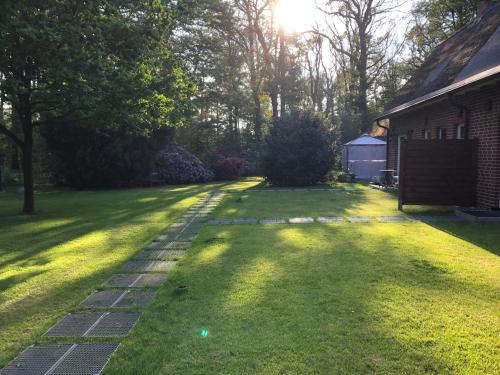 a backyard with a lawn with a brick path at Ferienwohnungen Unter den Eichen in Stade