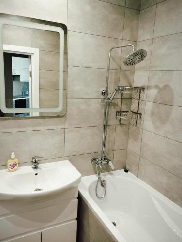 ein Badezimmer mit Waschbecken, Badewanne und Spiegel in der Unterkunft VIP квартира ЖК Київ Скай Рівненська, 4 in Luzk
