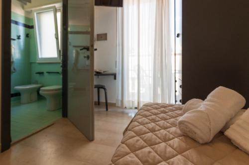 a bedroom with a bed and a bathroom with a toilet at Grand Meeting Hotel in Rimini