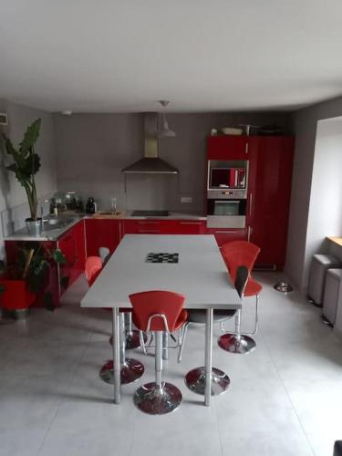 une cuisine avec des placards rouges, une table blanche et des chaises dans l'établissement Bienvenue chez vous !, à Jugeals-Nazareth
