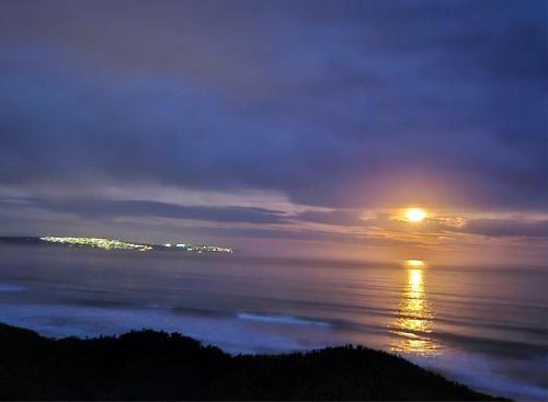 a view of the ocean at night with the sun at Kleinbos Beach Villa in Boggomsbaai