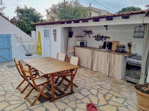 une table et des chaises en bois sur une terrasse dans l'établissement Jolie petite maison proche mer, à Valras-Plage