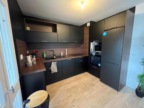 une cuisine avec des armoires noires et un plancher en bois dans l'établissement Skyview Appartement 4 Chambres, à Valence