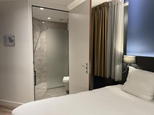 ホーフトドルプにあるOZO Hotels Antares Airportのベッドルーム1室(ベッド1台付)、バスルーム(シャワー付)が備わります。