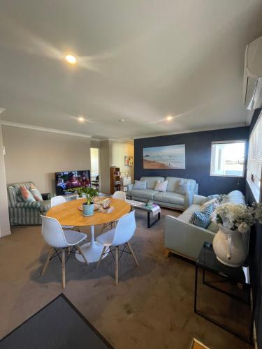 a living room with a table and a couch at Beach Apartment in Papamoa