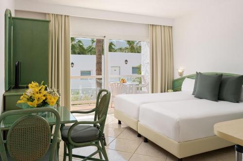 um quarto de hotel com uma cama, uma mesa e cadeiras em Aparthotel Esquinzo Y Monte Del Mar em Playa Jandia