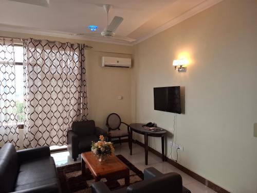 a living room with a couch and a tv at Flomi Hotel in Morogoro