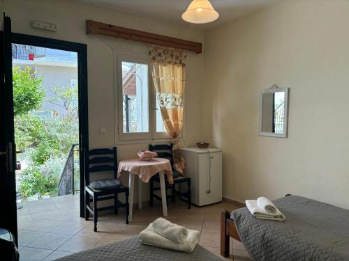 a room with two beds and a table and a window at Antigone's Studio in Kassiopi