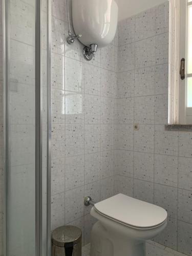 a white bathroom with a toilet and a window at VILLA MARELUNA - near the beach , family residence pet friendly ! in Capo Vaticano