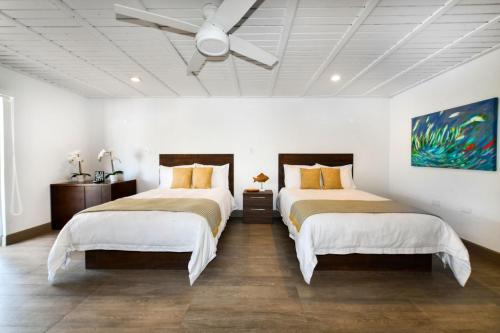 a bedroom with two beds and a ceiling fan at Aloe B&B in Oranjestad