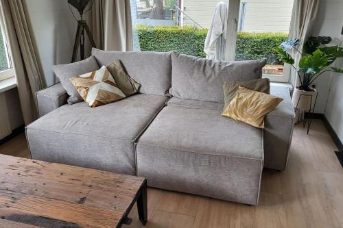 a gray couch with pillows in a living room at Family vibes, op 5 sterren vakantiepark in Limburg in Sevenum