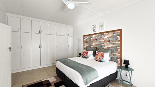 una camera da letto con un letto con armadi bianchi e un muro di mattoni di H cottages a East London