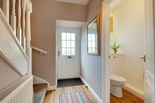 a bathroom with a toilet and a staircase with a mirror at Honeysuckle Cottage in Doddington
