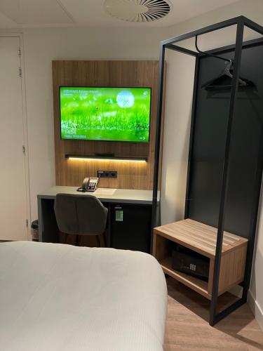 a bedroom with a bed and a desk with a television at OZO Hotels Antares Airport in Hoofddorp