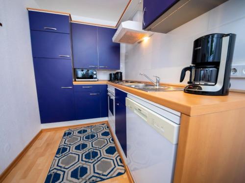 a small kitchen with blue cabinets and a sink at Holiday Home Neles Kate am Diemelsee by Interhome in Helminghausen