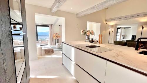 une cuisine avec des armoires blanches et un salon dans l'établissement Harmony by Zantos Montauroux, à Montauroux